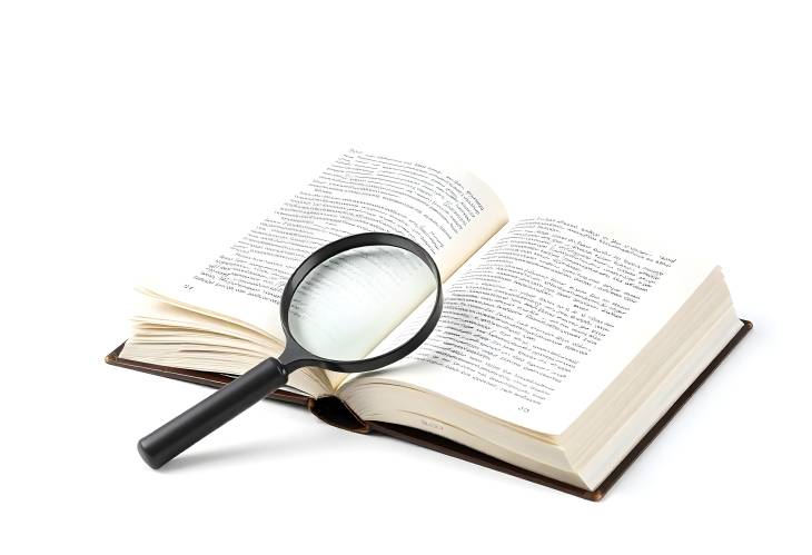 Closeup of Book and Magnifying Glass Highlighting Detailed Study